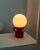 This beautiful table lamp in mid-century vintage style with a red ceramic base in steps and a white glass shade provides...