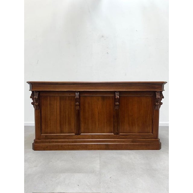 A stunning antique counter crafted in rich elm wood, featuring elegant carved details and a timeless paneled design. This...
