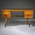 Low desk crafted in light beechwood, standing on tapered legs with black ribbed feet. The desk offers ample storage with...