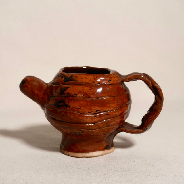 A beautifully expressive piece of handmade studio pottery featuring a rich, high-gloss red glaze with organic black...