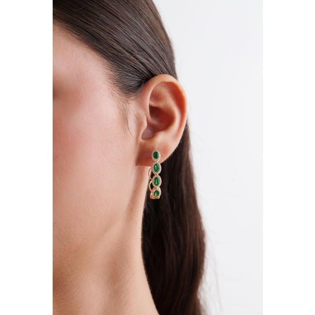 These modern hoop earrings feature 1.7 carats of natural oval emeralds, set in 14K yellow gold. Each emerald measuring 4.5...