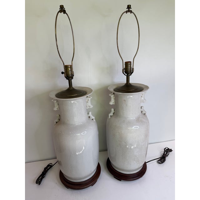 Exceptional pair of Chinese porcelain table lamps featuring a refined blanc de chine crackle glaze and traditional foo dog...