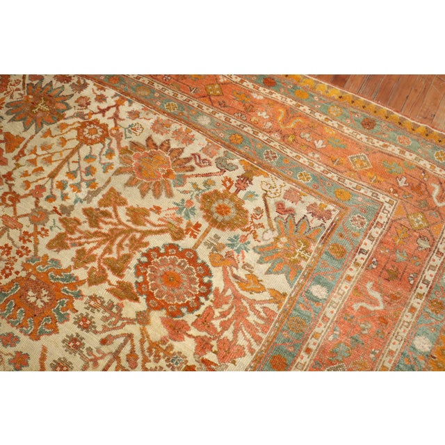 An early 20th-century room size Antique Turkish Oushak rug in predominantly ivory and orange with teal and brown...