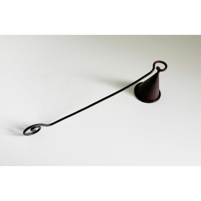 Rustic, primitive metal candle snuffer with turned and twisted scroll details on the handle. The metal features a rustic,...