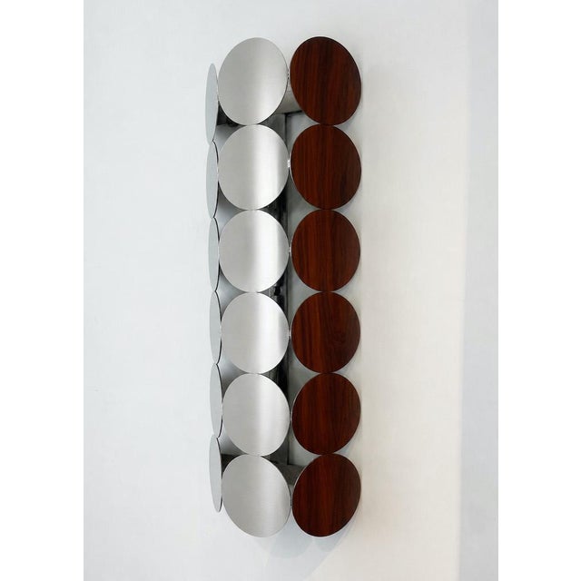 Unique wall sconce with a 1980s-style geometric and minimalist design, composed of metal discs with a satin silver finish,...