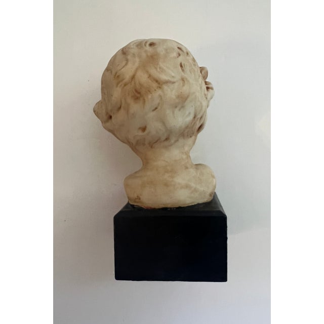 Small bust of baby’s head on wooden block