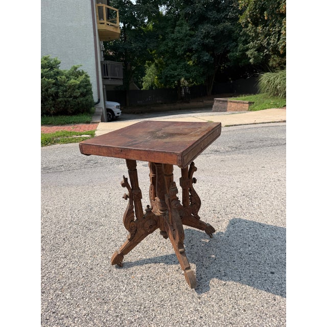 Antique Victorian barn house table made out of wood. The table features intricate carvings and wheels. The table is in...
