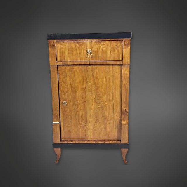 A small Biedermeier-era sideboard from southern Germany. The cabinet body is veneered in cherry wood. Above the door is a...