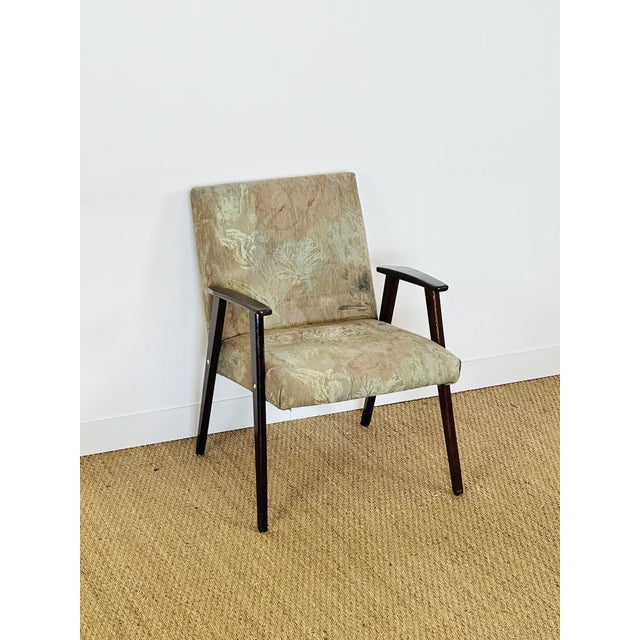 Vintage armchair with a scandinavian design typical of the mid-20th century. its dark-stained solid wood frame offers...