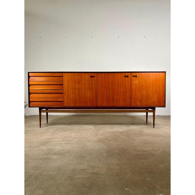An elegant, Scandinavian-inspired teak sideboard dating back to the 1960s or 1970s, characterized by a refined, minimalist...