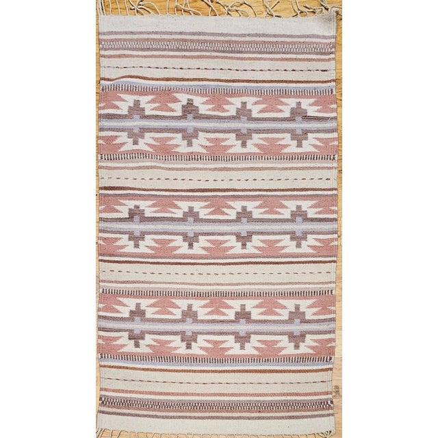 29” x 60” Vintage American Southwestern kilim area rug in gray, ivory, pink, and brown colors circa the late 20th century....