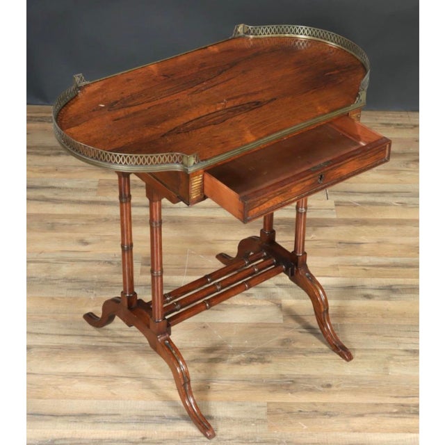An elegant early 19th-century English Regency rosewood writing desk featuring a beautifully figured rectangular top with...