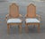 A matching duo of hand-carved fruitwood chairs, featuring classic woven cane backrests and plush upholstered seating.