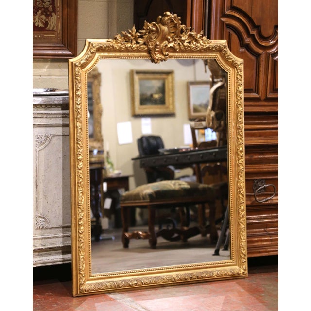 Crafted in France circa 1860, this elegant antique Louis XV wall mirror is distinguished by its richly carved giltwood...