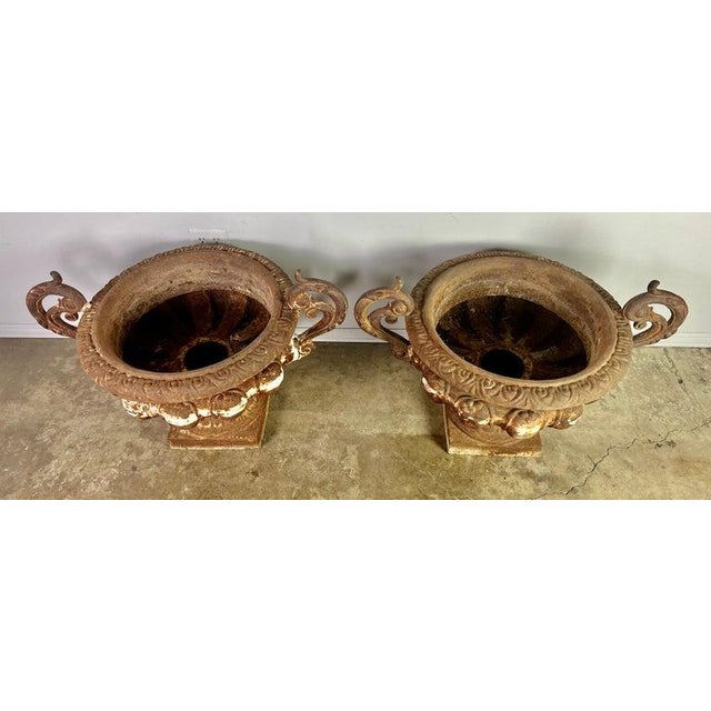 Impressive large pair of antique cast iron urn planters, European, early 20th century. Each planter features a wide,...