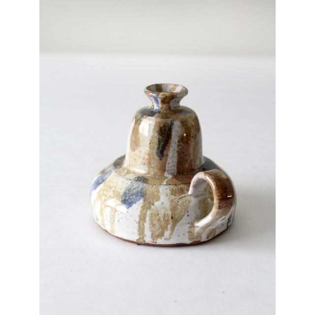 A vintage handmade studio pottery oil lamp, crafted in 1983, showcases a charming chamberstick design with a graceful...