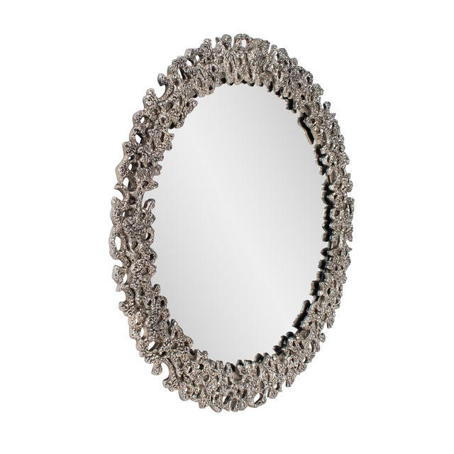 This stunning mirror is framed with an intricate, abstract design that mimics the organic texture of coral or lava rock....