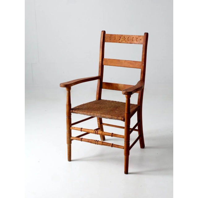 This is a vintage woven seat chair. The wooden arm chair features a herringbone basketweave seat with a floral carved top...