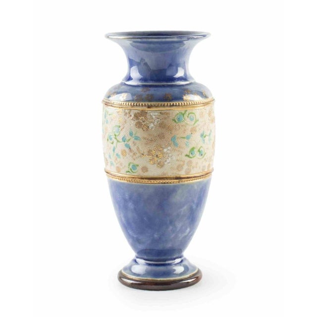 A refined, hand-painted ceramic vase featuring a rich cobalt blue glaze accented by an intricate central band with...