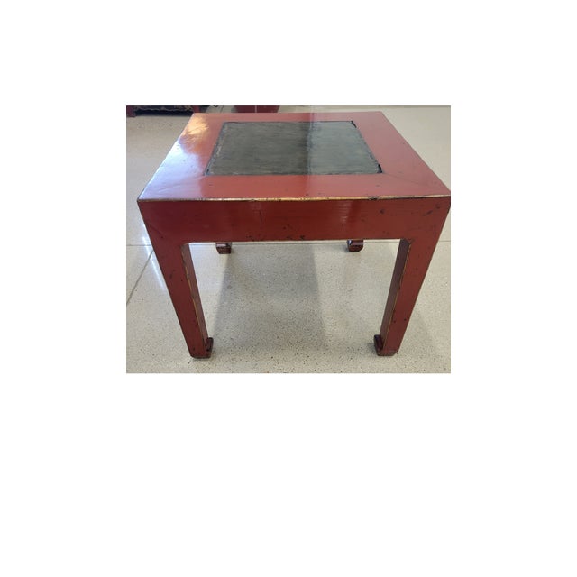 A classic Antique Chinese side table featuring a vibrant, hand-applied red painted finish and an inset dark slate stone...