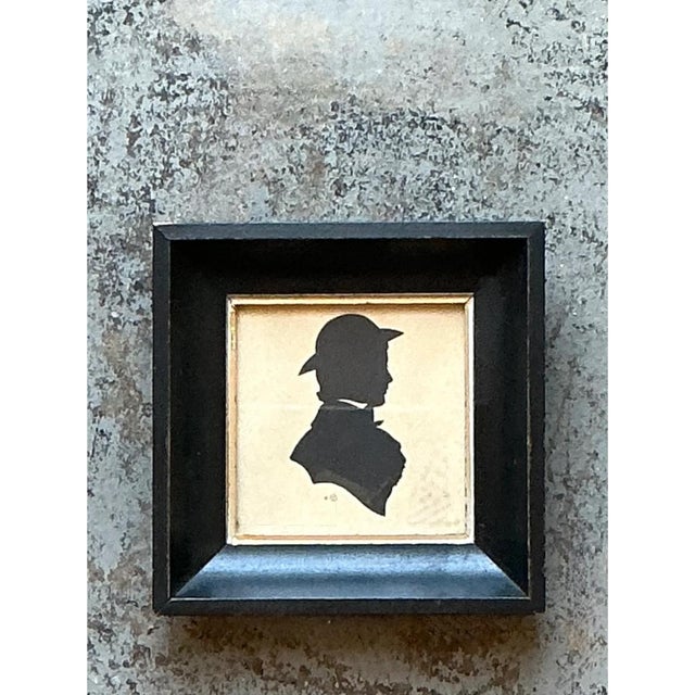 This vintage miniature portrait is a crisp profile silhouette of a figure facing right, cut in solid matte black paper and...