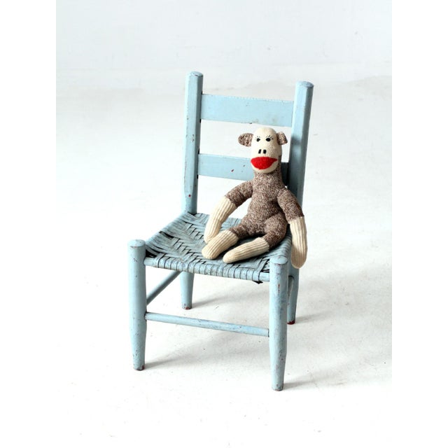 This charming antique children's chair features a rustic ladder back and woven splint seat. Painted in a light blue with a...