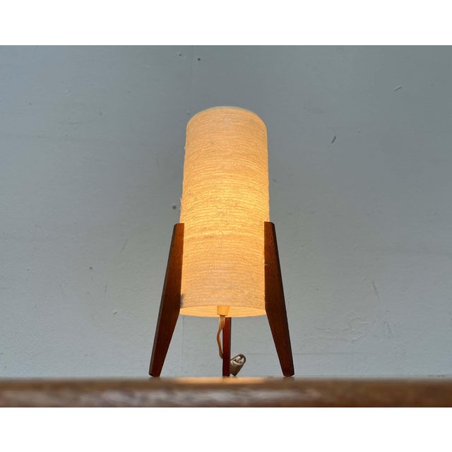 Small tripod table lamp from the 1960s. The diffuser is a simple cylinder made of a fiberglass-like material. It rests on...