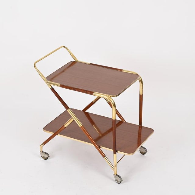 Marvelous and unique mid-century bar trolley entirely crafted in brass, wood and Formica. This refined serving cart was...