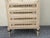 Elegant French Provincial jewelry armoire featuring an antiqued cream crackle finish, ornate floral carved detailing,...