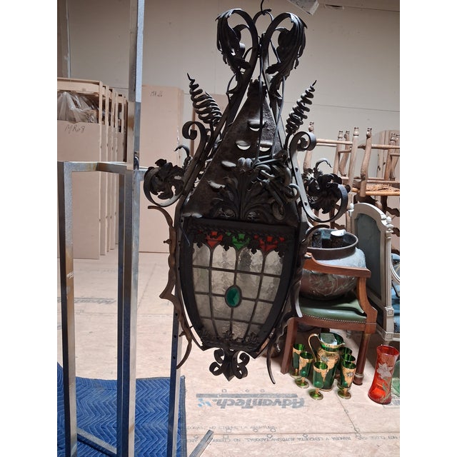 A striking French Gothic Revival hanging lantern handcrafted in wrought iron with beautifully detailed stained and...