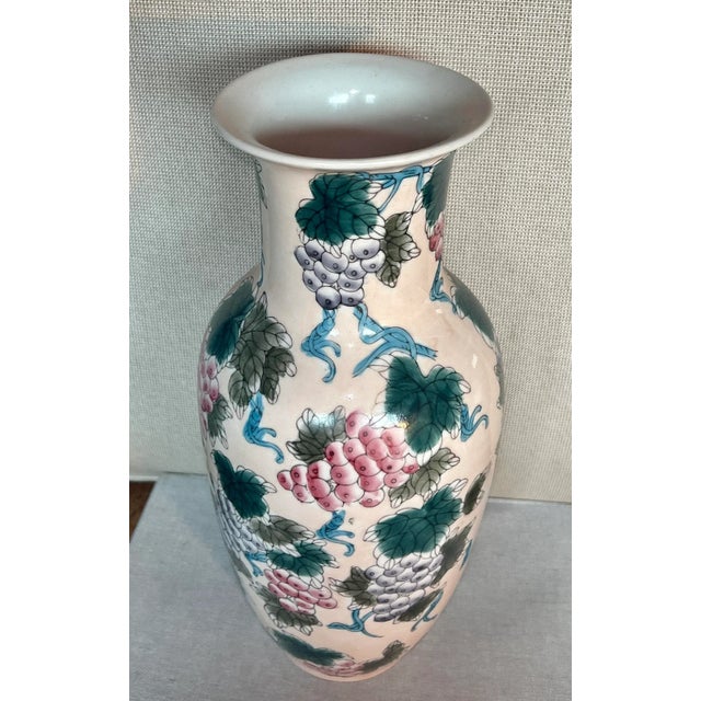Vintage light/pale pink, tall, chinoiserie vase. Made in China. Pale pink background. Leaves and grapes adorn this very...