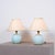Pair of Italian mid-century table lamps featuring rounded light blue glass bodies, circular brass bases and matching brass...