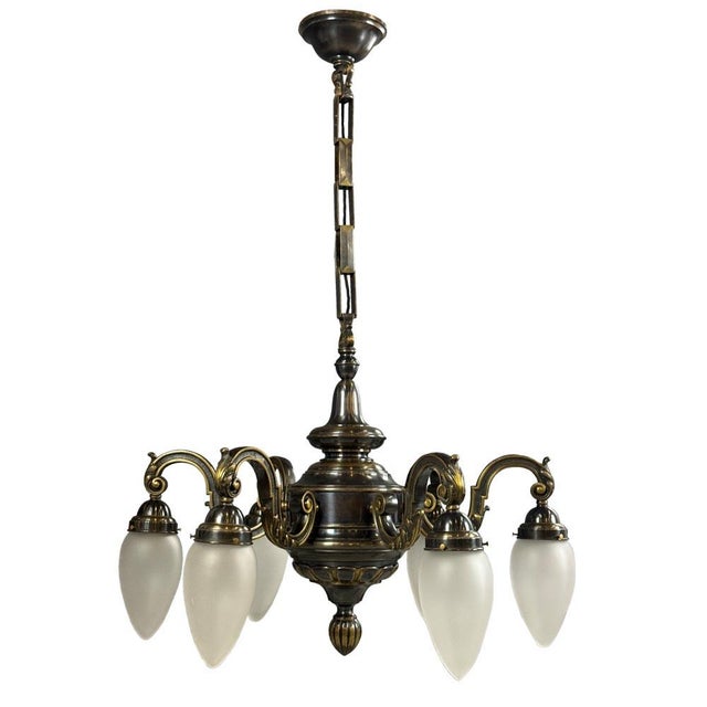 A decorative pendant chandelier featuring a richly shaped metal construction with refined ornamental details, reflecting...