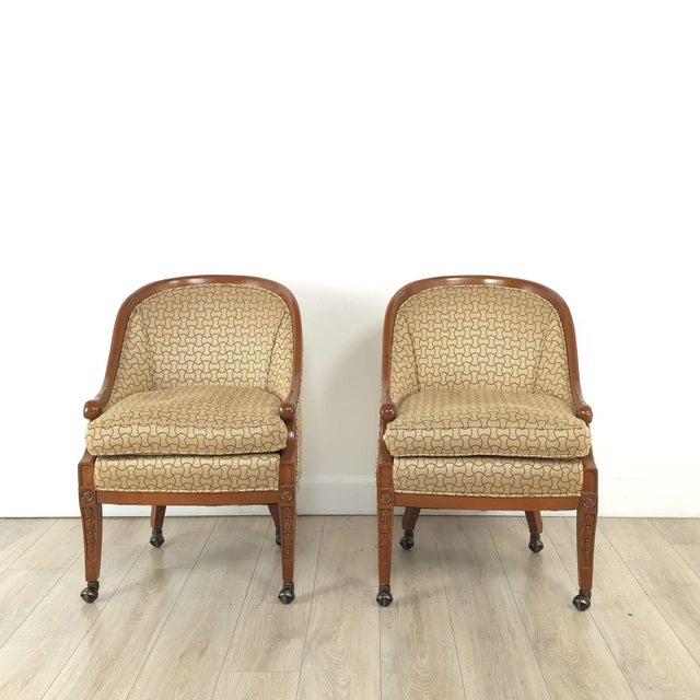 A pair of vintage Empire-style mahogany upholstered armchairs with casters. Seat height 21".
