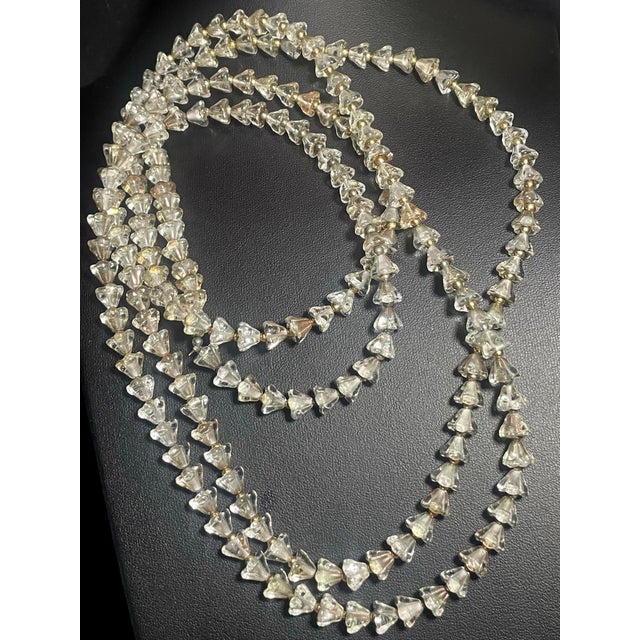 This long (62 inch) fluted necklace features transparent, mold-pressed glass bellflower (or trumpet flower) beads...