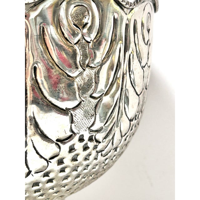 A stunning estate piece! It features a scalloped rim and elaborate embossed pattern, including figural and floral motifs....