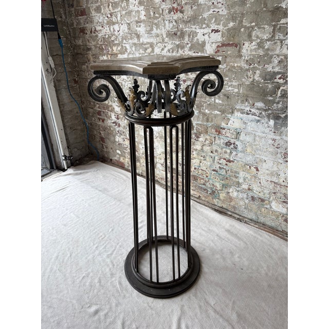 Striking vintage pedestal column featuring an ornate hand-forged iron base and sculptural marble top. The elegant...