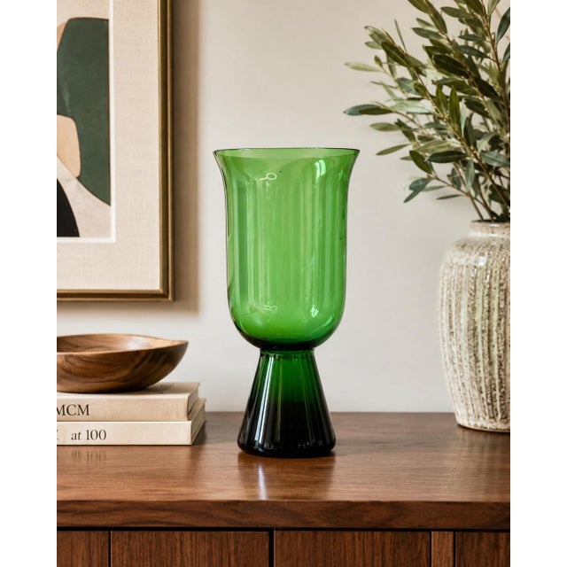 Striking vintage hand-blown art glass pedestal vase in rich emerald green, featuring a tall cylindrical body with a subtly...