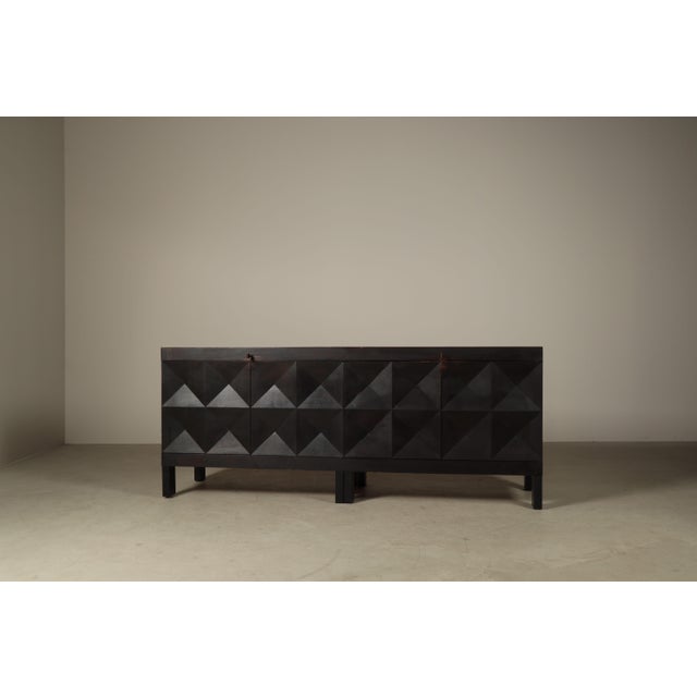 A brutalist four-door sideboard designed by jean batenburg for mi, belgium, during the 1960s, executed in solid ebonized...