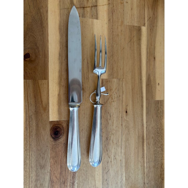 Christofle carving set comprising a carving knife and three-tine carving fork. Reeded silverplate handles bear the oval CC...