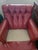 A handsome traditional leather club chair featuring rich oxblood-red leather upholstery, a deeply tufted backrest, rolled...