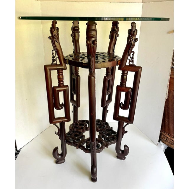 Here is a stunning, intricately carved rosewood table with a round glass top. The base is in the Hongmu Chinese style with...