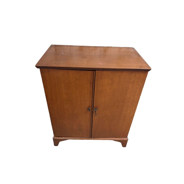 A stylish vintage Mid-Century Modern dry bar cabinet dating to the 1960s, featuring a clever flip-top design that combines...