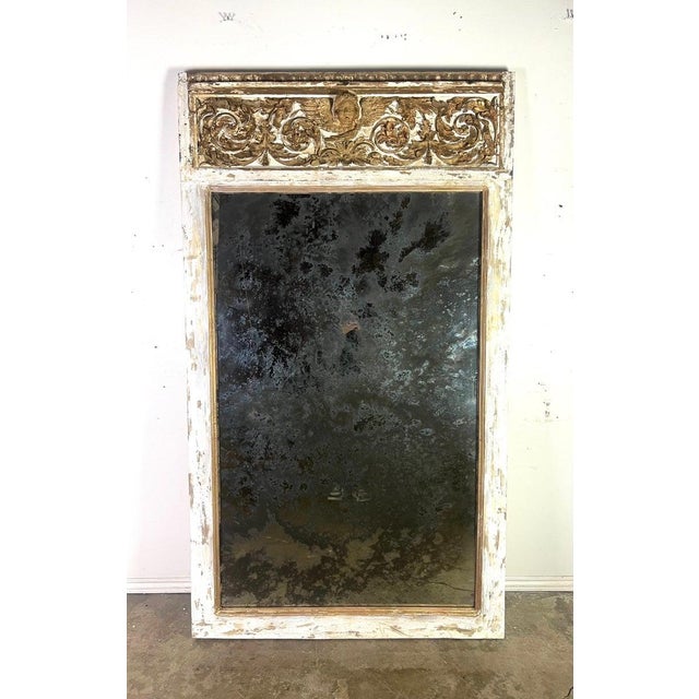 19th century Italian painted & parcel gilt mirror. The mirror frame features ornate carvings at the top, including floral...