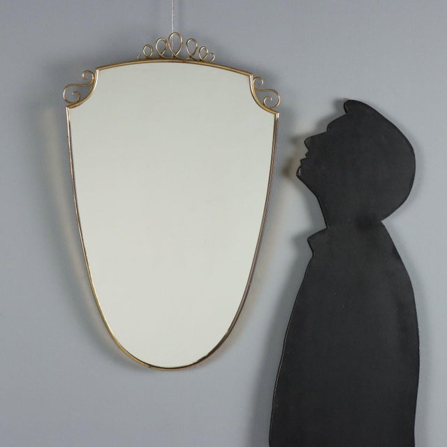 Wall mirror dating back to the 1950s-60s, featuring a brass frame with elegant spiral decorations that add a touch of...