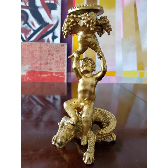 A museum quality 18th century French bronze ormolu candle holder. Having a chubby baby cupid with wings on top of a...