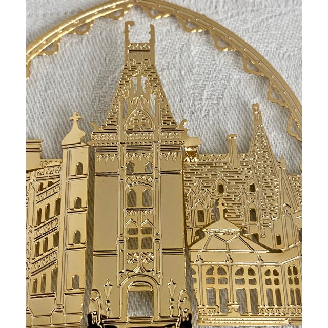 This is a Biltmore Estate house Christmas ornament featuring a 24-karat gold finish. The set includes a maroon display box...