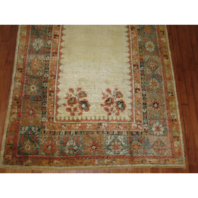 An early 20th century angora wool Oushak rug with a ivory colored field with other subtle warm accents in orange and...