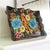 This wooden scalloped tray is hand-painted in a Mexican Folk Art style, depicting flowers and a large bird or parrot in...