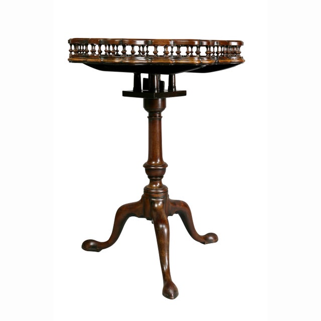 Tilt top table with circular shaped spindled gallery raised on a turned urn form support and three cabriole legs with pad...